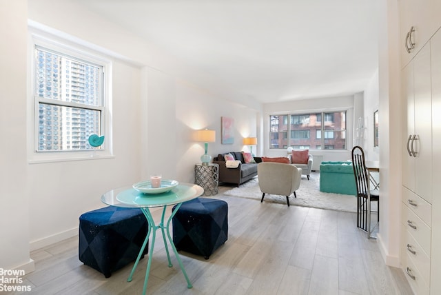 dining room with light wood-style floors, a healthy amount of sunlight, and baseboards