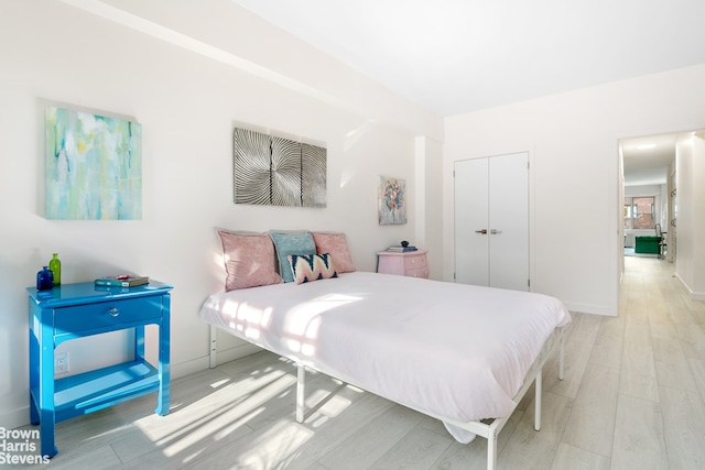 bedroom featuring a closet, light wood-type flooring, and baseboards