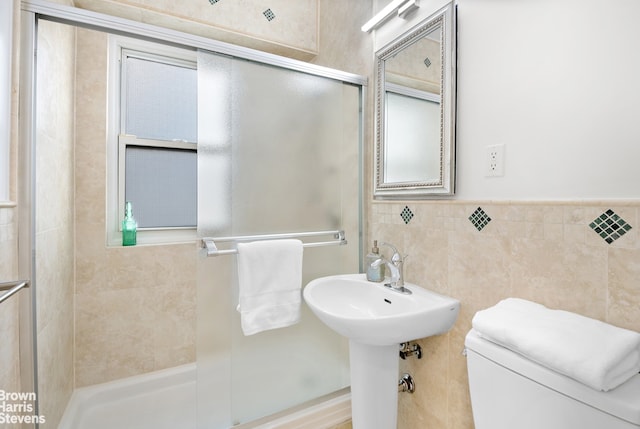 full bathroom with tile walls, a shower stall, and toilet