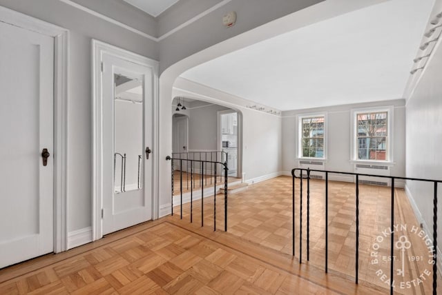 hallway featuring arched walkways and baseboards