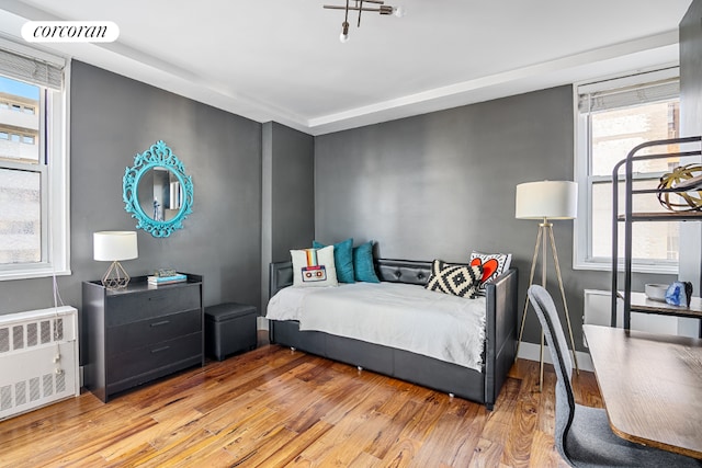 bedroom featuring radiator, light wood finished floors, baseboards, and visible vents