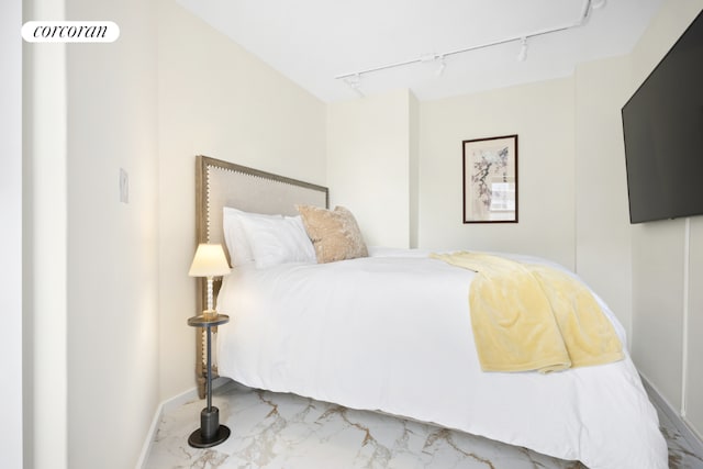 bedroom with baseboards, marble finish floor, and track lighting