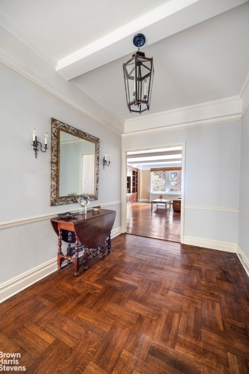 hallway with a chandelier, crown molding, and baseboards