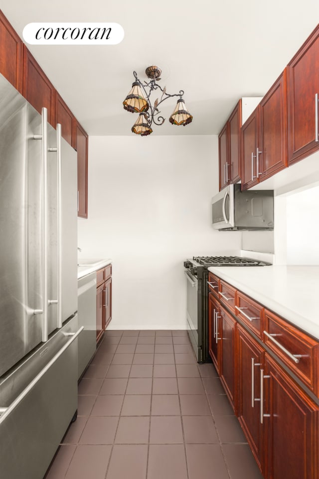 kitchen featuring dark brown cabinets, appliances with stainless steel finishes, light countertops, and dark tile patterned flooring