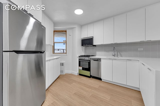 kitchen featuring white cabinets, a sink, stainless steel appliances, and light countertops