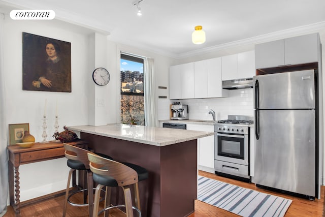 kitchen featuring crown molding, stainless steel appliances, visible vents, light wood-style flooring, and under cabinet range hood