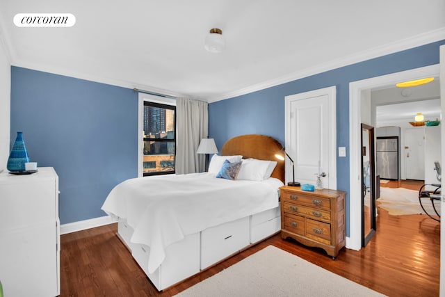 bedroom featuring baseboards, visible vents, dark wood finished floors, freestanding refrigerator, and crown molding