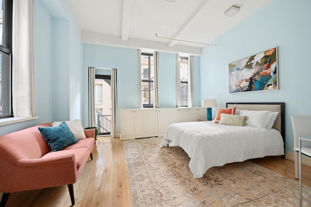 bedroom with beamed ceiling, attic access, and light wood finished floors