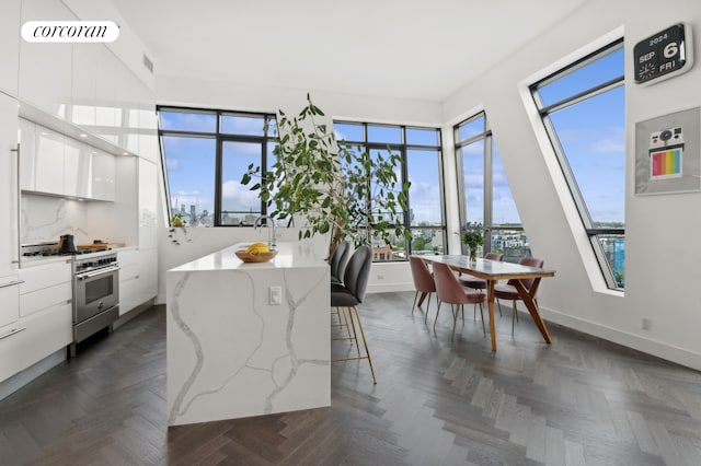 kitchen with modern cabinets, a breakfast bar, a center island, white cabinetry, and stainless steel stove