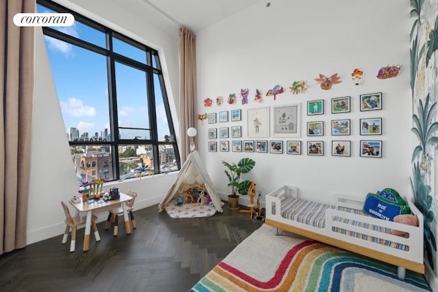 recreation room with a healthy amount of sunlight, baseboards, and a city view