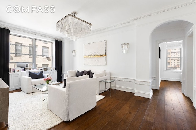 living room with arched walkways, dark wood-style flooring, and crown molding