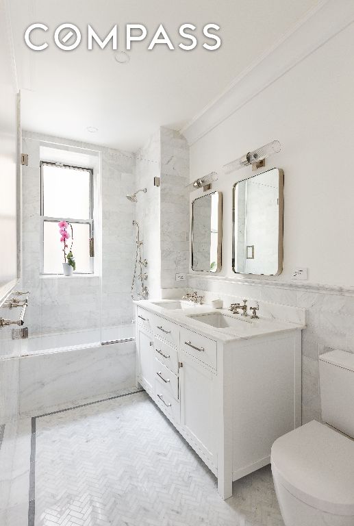 full bathroom featuring a combined bath / shower with marble appearance, a wainscoted wall, a sink, and tile walls