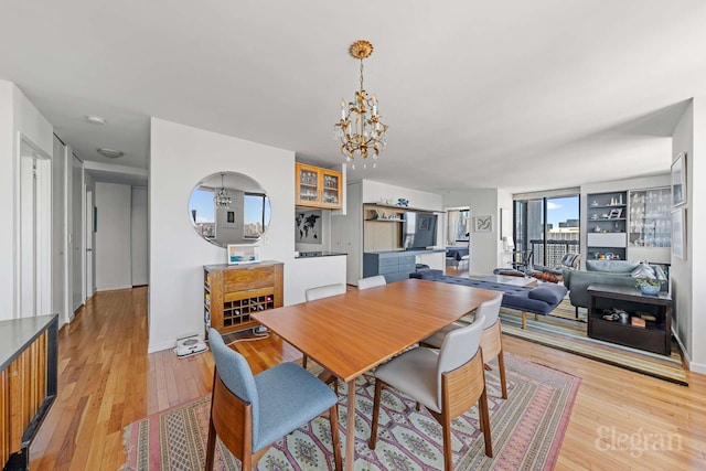 dining area with an inviting chandelier, baseboards, and light wood-type flooring