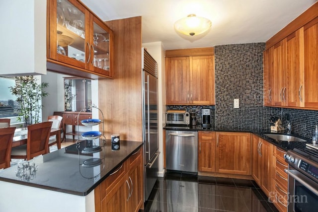 kitchen with stainless steel appliances, tasteful backsplash, glass insert cabinets, and brown cabinets