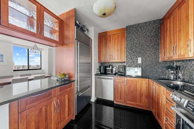 kitchen with appliances with stainless steel finishes, granite finish floor, an inviting chandelier, and tasteful backsplash