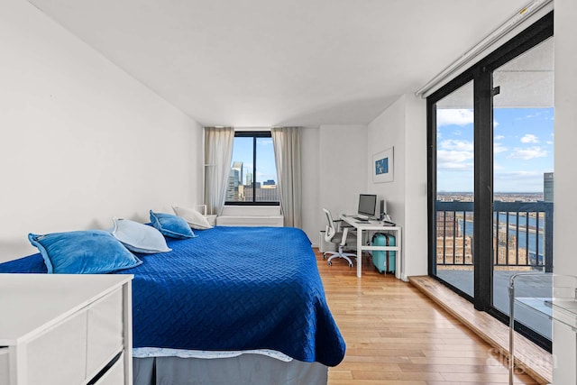 bedroom with expansive windows, access to exterior, and light wood-style flooring