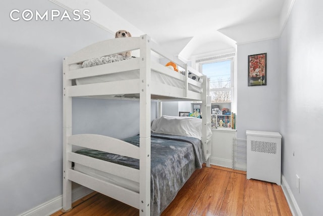 bedroom featuring radiator, baseboards, and wood finished floors