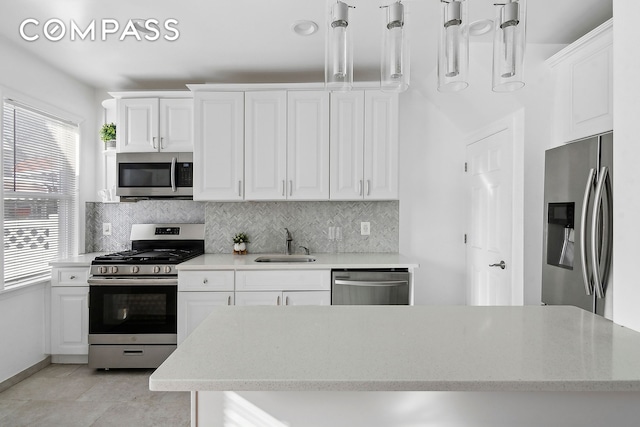 kitchen featuring white cabinets, decorative backsplash, stainless steel appliances, and a sink