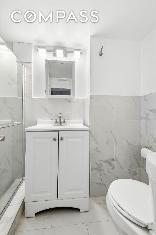 bathroom featuring a stall shower, marble finish floor, vanity, and toilet