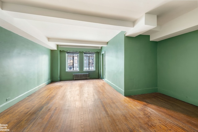 spare room with beamed ceiling, hardwood / wood-style floors, radiator heating unit, and baseboards