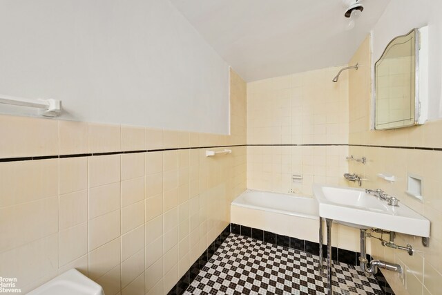 bathroom featuring washtub / shower combination and tile walls