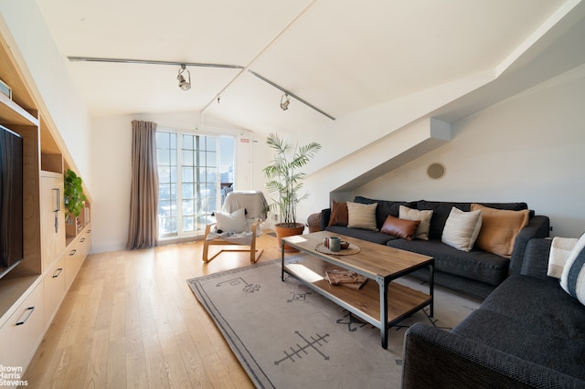 living room featuring lofted ceiling, light wood-style flooring, and rail lighting