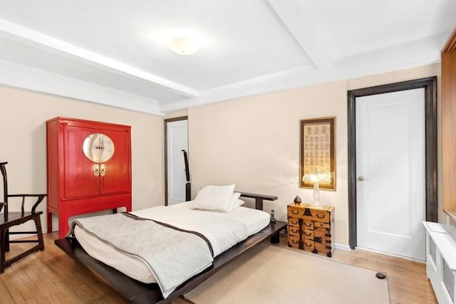 bedroom featuring beamed ceiling and wood finished floors