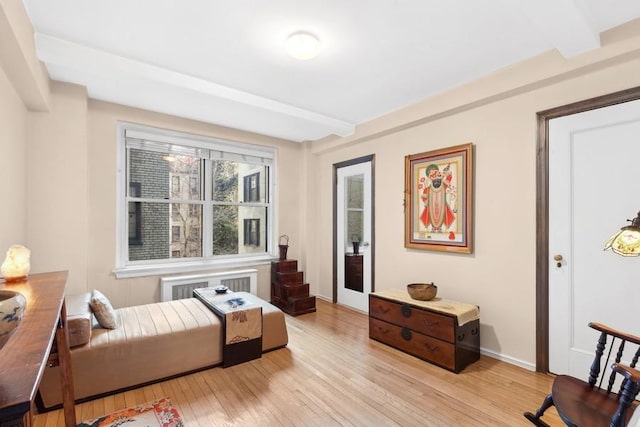 sitting room featuring radiator, light wood-style flooring, baseboards, and beamed ceiling