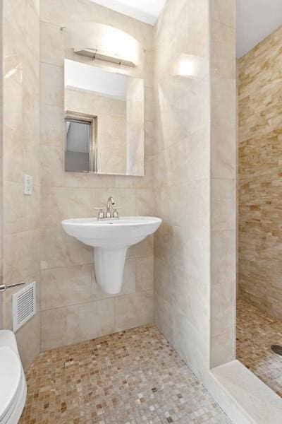 full bathroom with visible vents, tile walls, toilet, and tiled shower