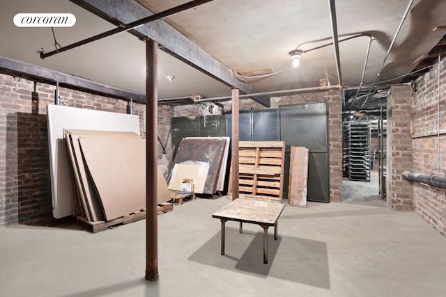 unfinished basement featuring visible vents and brick wall