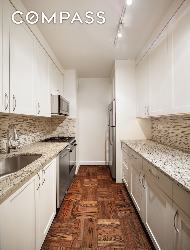 kitchen featuring a sink, appliances with stainless steel finishes, tasteful backsplash, and light stone counters