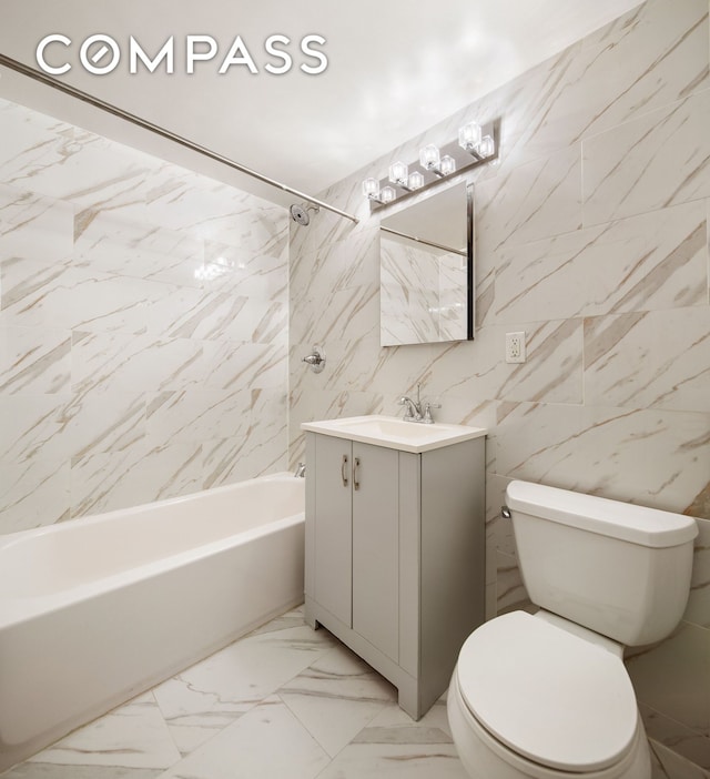 full bath with marble look tile flooring, toilet, shower / bathtub combination, vanity, and tile walls