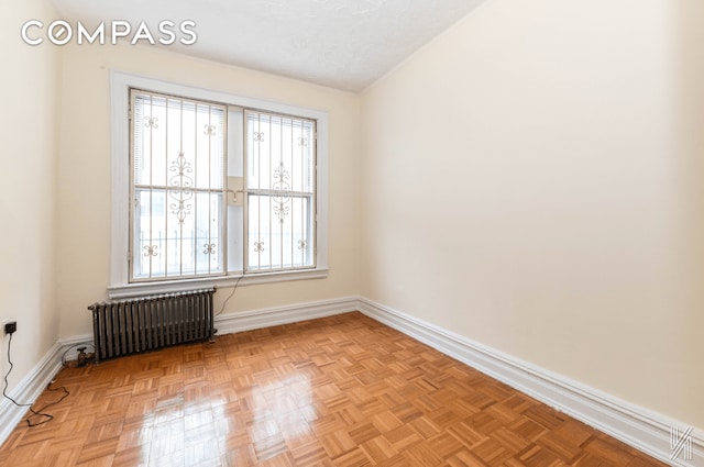 unfurnished room with radiator, a textured ceiling, and baseboards