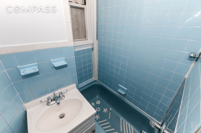 bathroom with shower / bathing tub combination, tile walls, and vanity