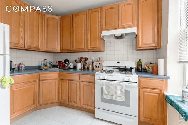 kitchen featuring dark countertops, white appliances, tasteful backsplash, and under cabinet range hood