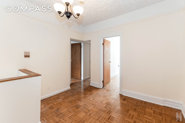 unfurnished room with an inviting chandelier, baseboards, and a textured ceiling