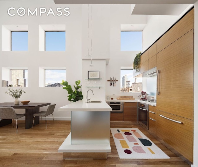 kitchen featuring brown cabinets, light countertops, stainless steel oven, and modern cabinets