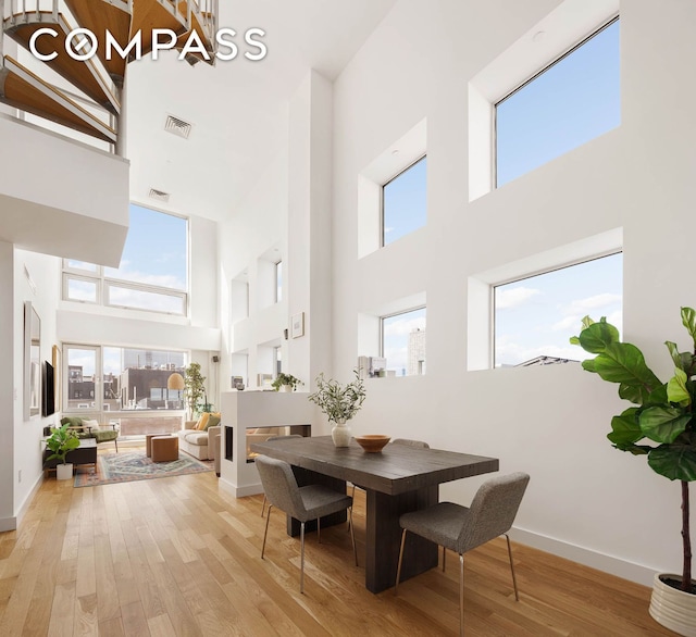 dining room featuring baseboards, light wood-type flooring, visible vents, and a healthy amount of sunlight