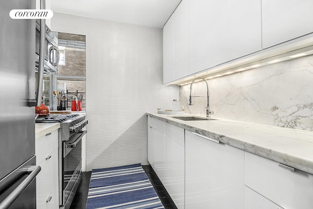 kitchen featuring tasteful backsplash, appliances with stainless steel finishes, a sink, white cabinetry, and modern cabinets