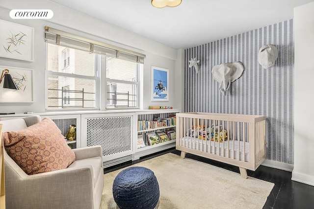 bedroom with baseboards, wallpapered walls, wood finished floors, and visible vents