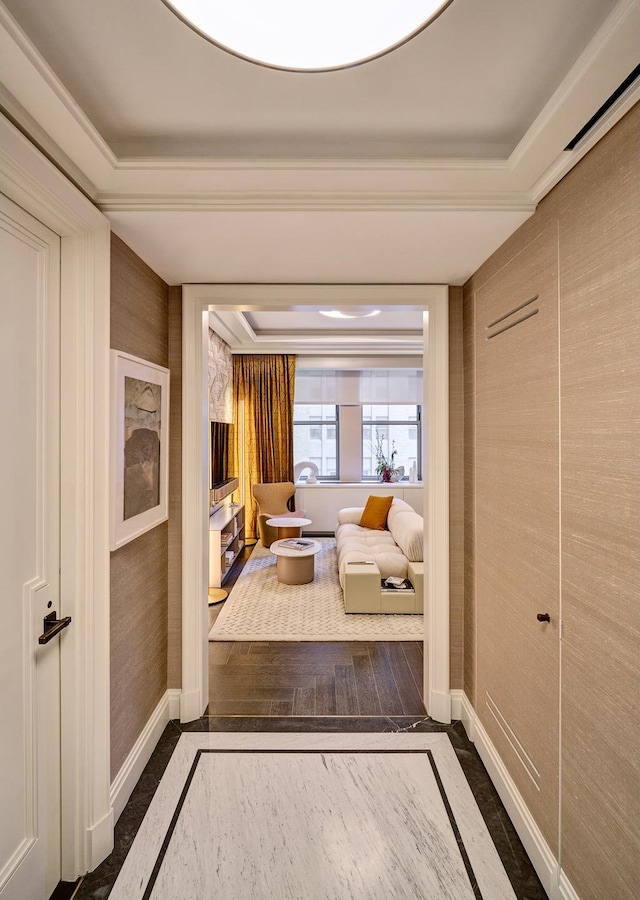 hallway featuring wood finished floors, a raised ceiling, baseboards, and wallpapered walls