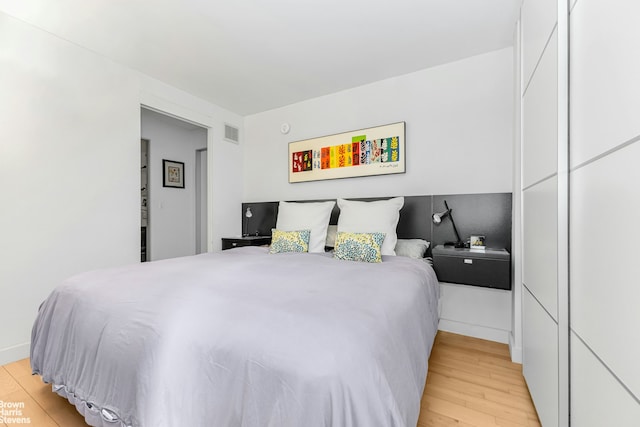 bedroom with light wood-style floors and visible vents