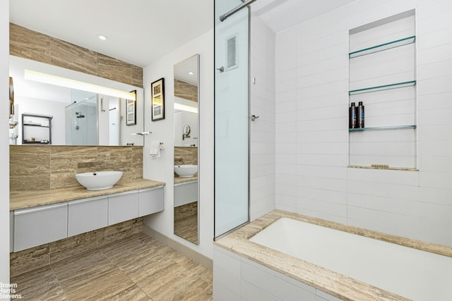 full bathroom with tasteful backsplash, a stall shower, a bath, and a sink