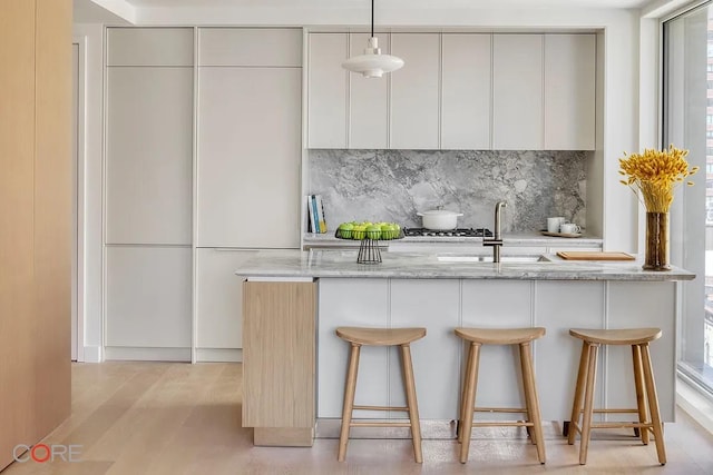 kitchen featuring a breakfast bar area, backsplash, a sink, and modern cabinets