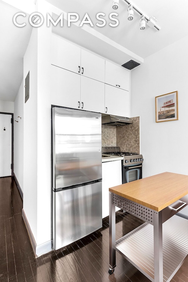 57 Thompson St Unit 2B, New York City, NY 10012 - kitchen featuring stainless steel appliances, under cabinet range hood, dark wood-type flooring, tasteful backsplash, and white cabinets