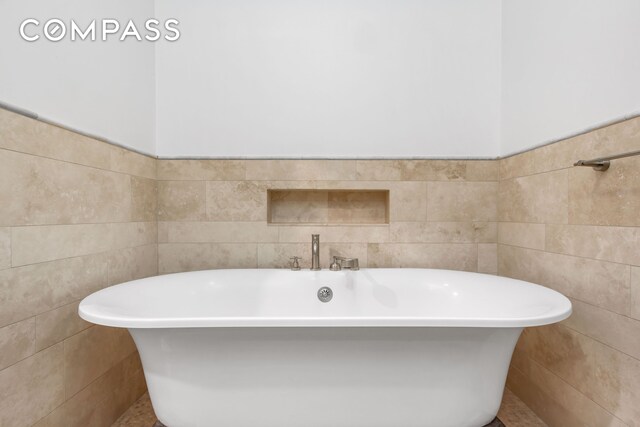 bathroom with a freestanding tub and tile walls