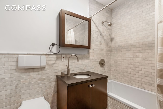 full bath featuring tiled shower / bath combo, tile walls, toilet, and vanity