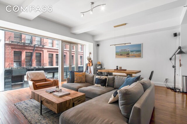 living area with wood finished floors, beam ceiling, and baseboards