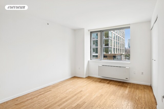 425 Main St Unit 3P, New York City, NY 10044 - spare room with radiator heating unit, baseboards, wood finished floors, and visible vents