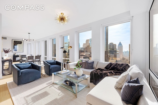 living room featuring light wood-style floors, a notable chandelier, and a city view